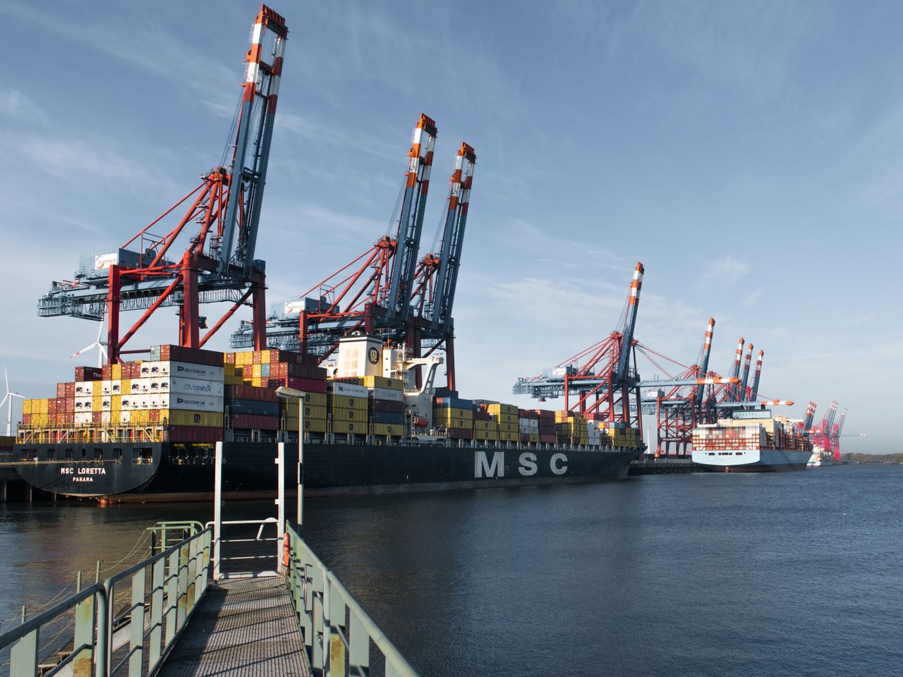 services-04 Container ships docked at Hamburg port with cranes loading cargo under clear skies.
