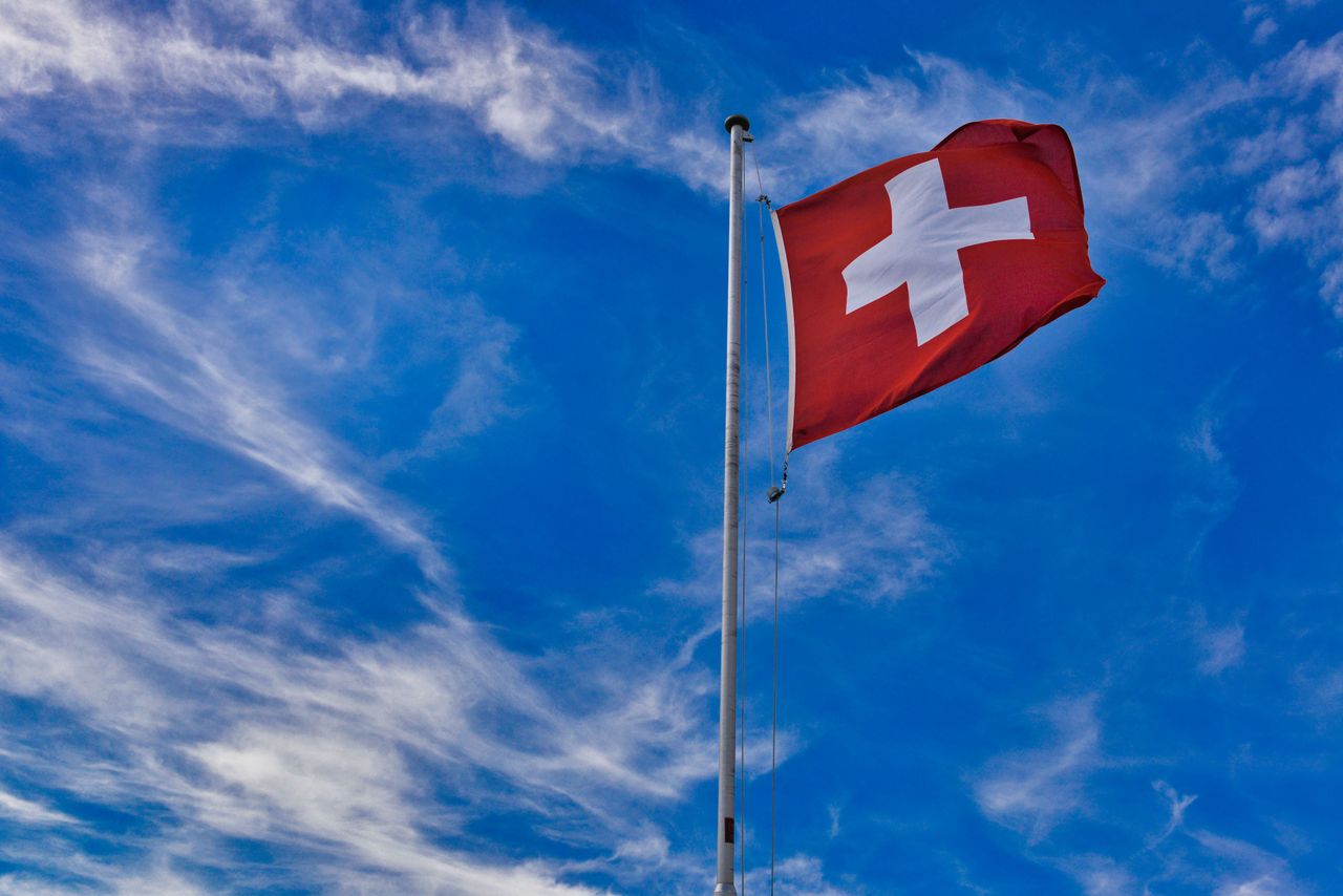 services-02 Swiss flag on a mast waving against the vivid blue sky in Grindelwald, Switzerland.