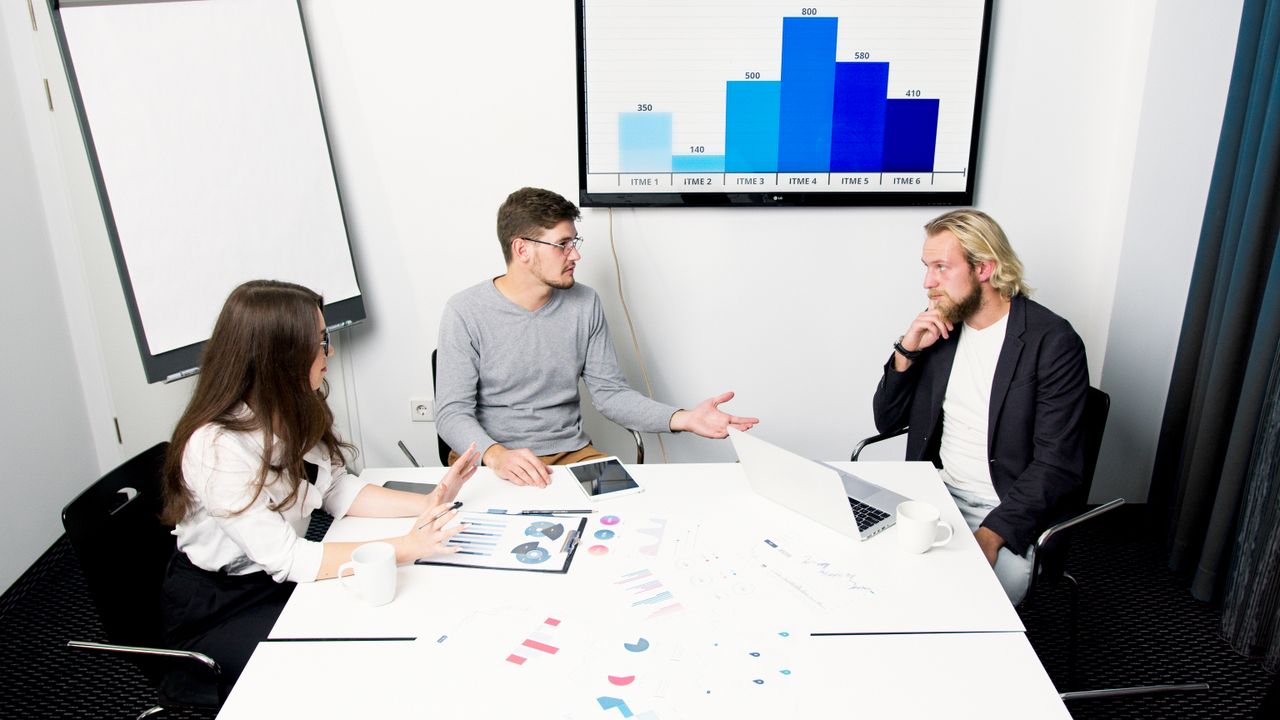 Professional team discusses strategies in a modern office environment with digital charts.