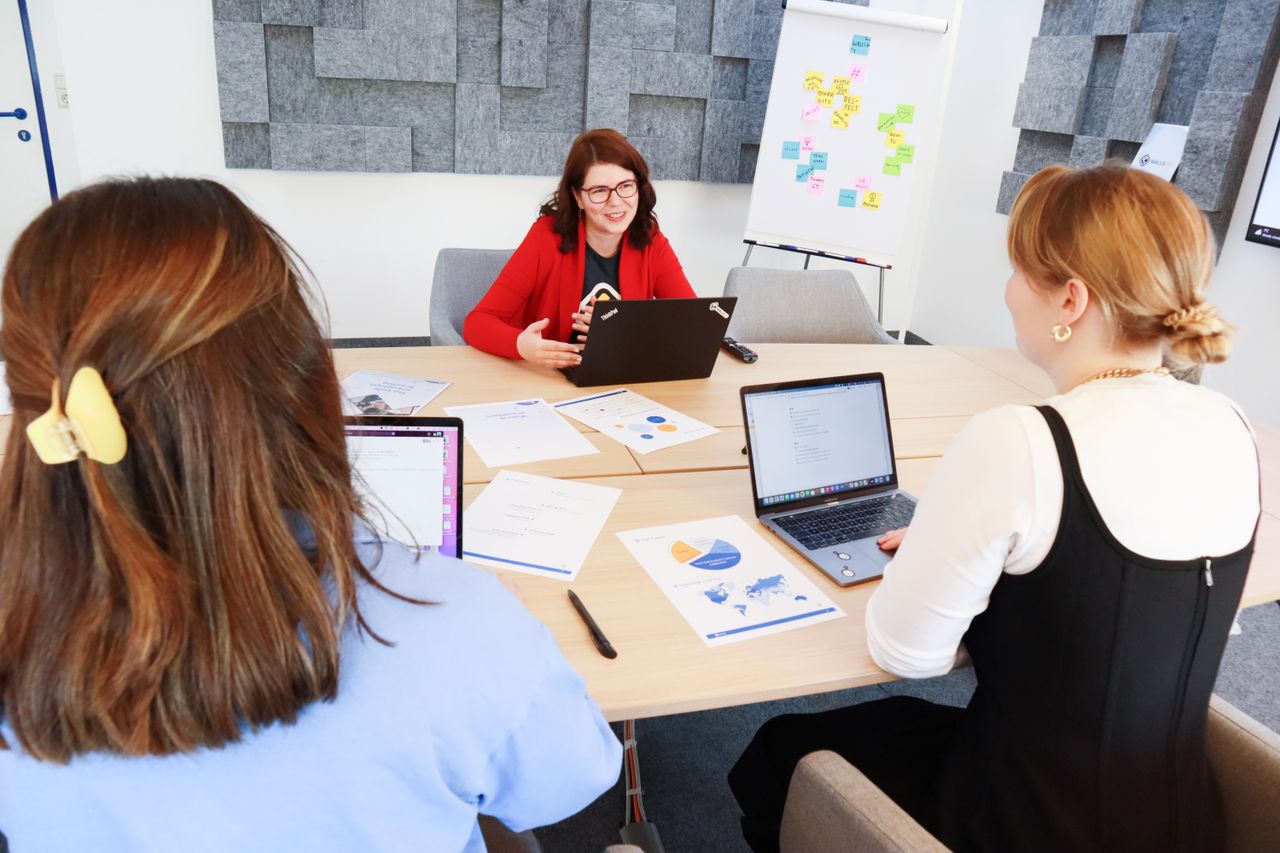 Women discussing business strategy in an office with laptops and charts.